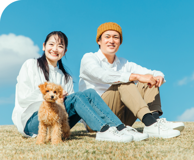 芝生の上で愛犬とくつろぐカップル