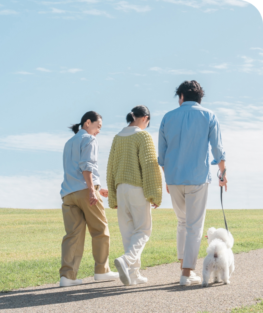 青空の下で犬を散歩する家族